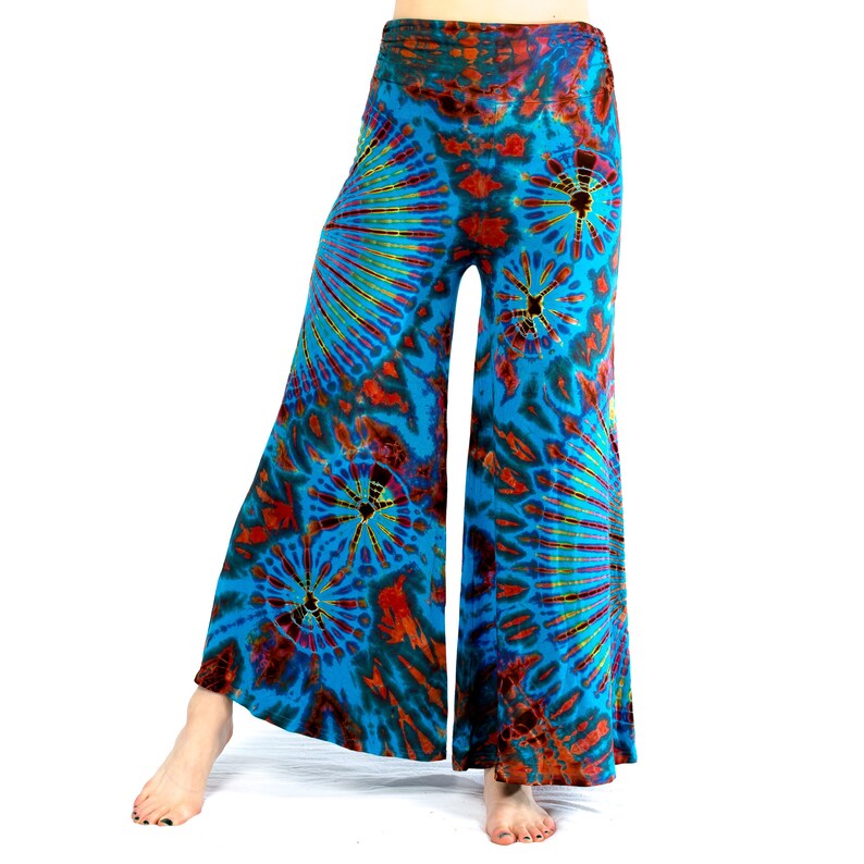 May include: Wide-leg trousers with a vibrant tie-dye pattern in shades of turquoise, orange, and yellow. The trousers feature a high waistband and a flared silhouette, creating a bohemian style.