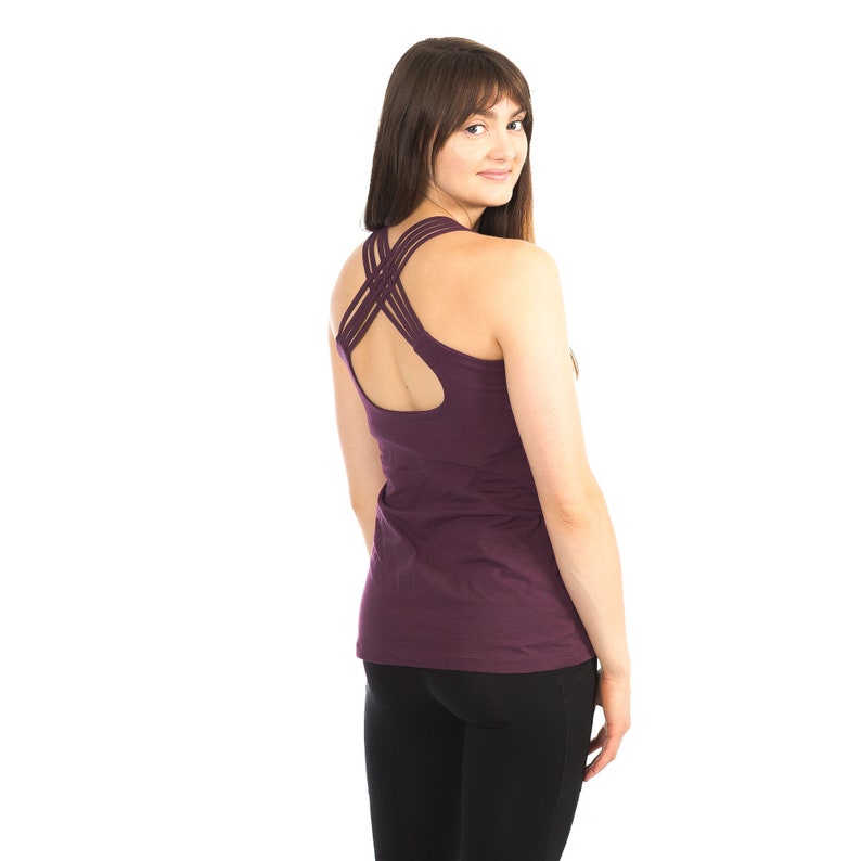 May include: A purple tank top with a criss-cross back design. The tank top is made of a soft, comfortable fabric and has a relaxed fit.