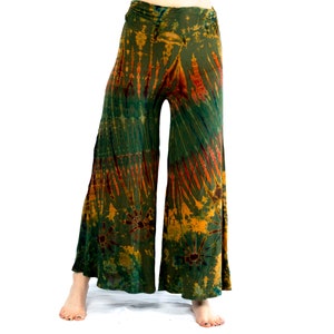 May include: Tie-dye wide-leg trousers in green, orange, and yellow. The trousers have an elasticated waistband and a flowing shape. The tie-dye design features vertical and circular patterns. The trousers are made of a soft, flowing fabric.