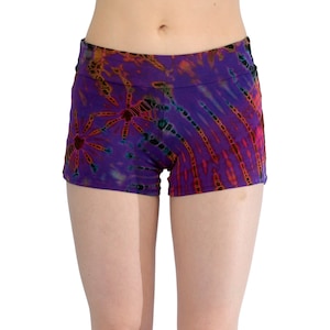 Op de afbeelding: Paarse tie-dye shorts met een zwarte tailleband. De shorts hebben een kleurrijk patroon met oranje, rode en blauwe accenten.