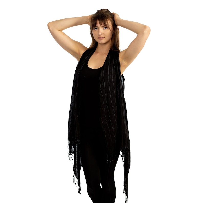 May include: A black sleeveless top with a striped pattern and a fringed hem. The top is worn over a black vest top.