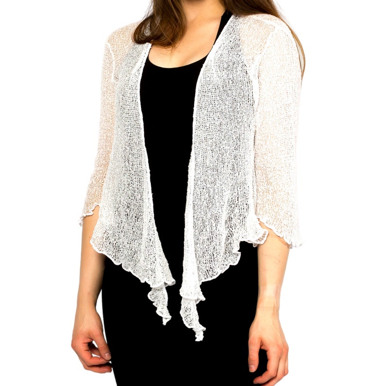 Op de afbeelding: Witte gehaakte shrug met een delicate open structuur en een licht gekrulde zoom.