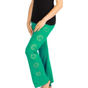 Può includere: Pantaloni da yoga verdi con simboli dorati dei chakra stampati sulle gambe. I pantaloni sono svasati e hanno una vestibilità rilassata.