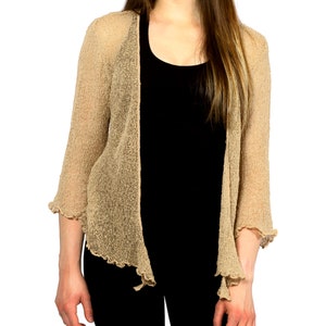 Op de afbeelding: Een beige open cardigan met een losse, vloeiende pasvorm en een gegolfde zoom. De cardigan is gemaakt van een lichtgewicht, doorschijnende stof.