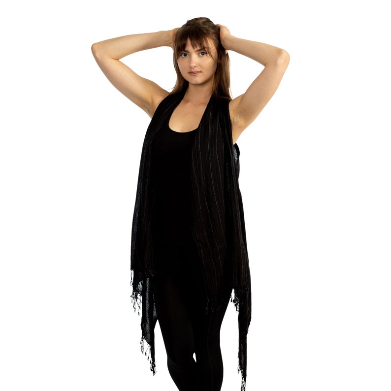 May include: A woman wearing a black sleeveless top with a striped pattern and a black vest with a fringe trim.