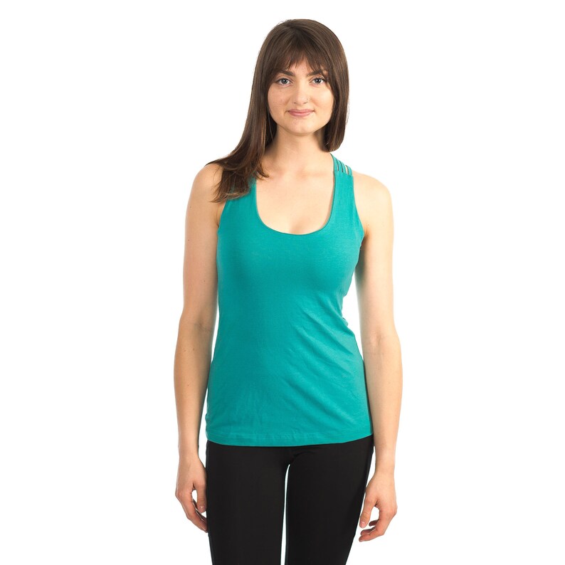 May include: A woman wearing a teal tank top with a racerback design and black trousers.