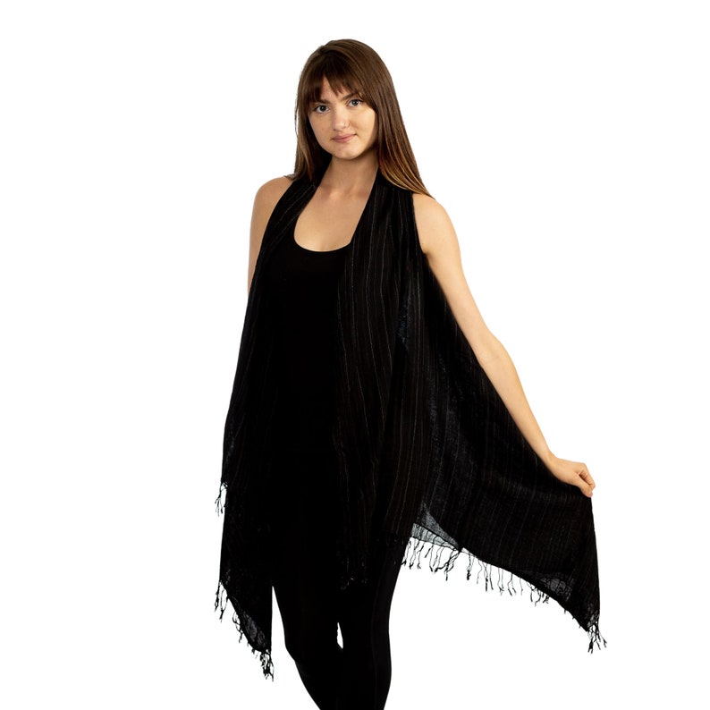 May include: A black sleeveless vest with a striped pattern and fringe trim. The vest is made from a lightweight fabric and has a relaxed fit.