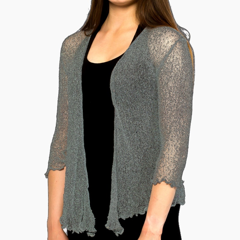 Op de afbeelding: Een grijze, open, lichtgewicht gebreide cardigan met 3/4 mouwen. De cardigan heeft een delicate, kant-achtige textuur.