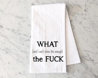 May include: White kitchen towel with black text that reads "WHAT (and I can't stress this enough) the FUCK". The towel is folded and lies on a marble surface.