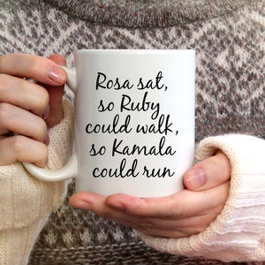 May include: White ceramic mug with black text that reads "Rosa sat, so Ruby could walk, so Kamala could run".