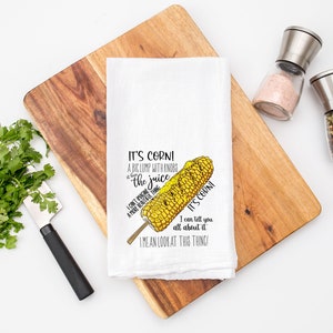 May include: White kitchen towel with a drawing of a corn cob and the text "It's corn! A big lump with knobs and the juice. I can't imagine a more beautiful thing. It's corn! I can tell you all about it. I mean look at this thing!"