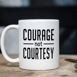 Peut inclure: Une tasse &agrave; caf&eacute; en c&eacute;ramique blanche avec du texte noir qui dit "COURAGE not COURTESY".