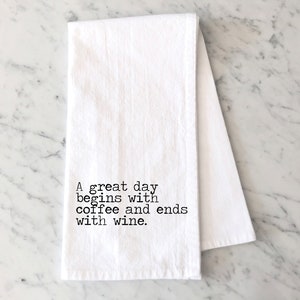 May include: White kitchen towel with black text that reads "A great day begins with coffee and ends with wine."