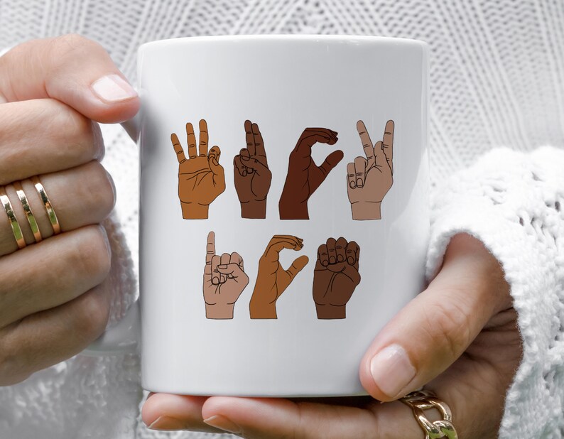 K&ouml;nnte beinhalten: Wei&szlig;er Keramikbecher mit Illustrationen von H&auml;nden, die das Wort "LOVE" in amerikanischer Geb&auml;rdensprache buchstabieren. Die H&auml;nde sind in verschiedenen Hautt&ouml;nen dargestellt, mit einem einfachen Design. Der Becher wird von einer Person gehalten.