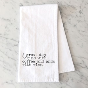 May include: White kitchen towel with black text that reads "A great day begins with coffee and ends with wine."