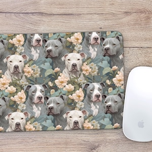 May include: A mouse pad featuring a repeating pattern of grey and white pit bull terriers with floral accents. The background is a light blue with green leaves and white flowers.