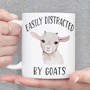 May include: White ceramic mug with a black and white illustration of a goat and the text "Easily Distracted by Goats".