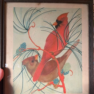 May include: Framed vintage print featuring two cardinal birds perched on a branch with pine needles and cones. The male cardinal is bright red, the female is brown. The print has text that reads "CARDINAL". The frame is dark brown.