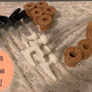 May include: An assortment of clear plastic pump dispensers with black and white pump heads, alongside several cork bottle stoppers. The image is taken on a white lace tablecloth. The text "ships in one day!" is in a peach circle.