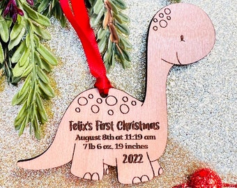 May include: A wooden dinosaur ornament with a red ribbon. The ornament is personalized with the text "Felix's First Christmas", "August 8th at 11:19 am", "7 lb 6 oz, 19 inches", and "2022".