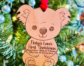 May include: A wooden koala ornament with the text "Naiya Love's First Christmas" and "November 20th at 7:55am 9lbs 1oz 19 1/2 inches" and "2023".