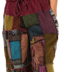 Puede incluir: Pantalones patchwork multicolores con cintura con cordón. Los pantalones presentan un diseño de patchwork hecho de cuadrados de tela en tonos burdeos, verdes, azules y morados. Tienen un ajuste holgado y cómodo.