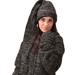 Peut inclure: Un pull en tricot noir et gris avec un bonnet et une écharpe assortis. Le bonnet a une longue écharpe attachée qui peut être portée comme une capuche. Le pull a une poche sur le devant et un pompon sur la manche.