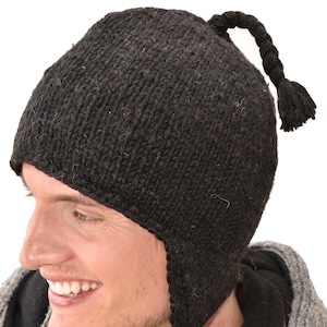 May include: A black knitted hat with ear flaps and a braided tail. The hat is made of wool and has a warm, cozy feel.