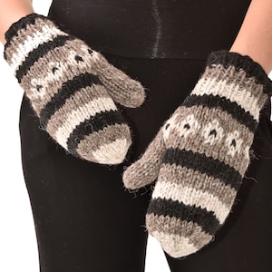 May include: A pair of grey and black striped knitted mittens with a white pattern. The mittens are made of wool and have a warm, cosy feel.