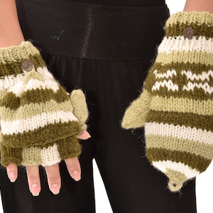 May include: A pair of olive green, white, and light green knitted convertible mittens. The mittens have a button closure and a flap that can be flipped back to expose the fingers. The mittens are designed with horizontal stripes and a zig-zag pattern.