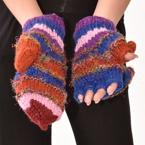 May include: A pair of fingerless gloves with a striped pattern in shades of blue, pink, orange, and brown. The gloves have a thumb hole and a folded cuff.