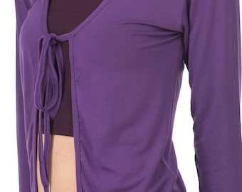May include: A purple long-sleeved wrap top with a tie at the front. The top is worn over a black tank top and black pants.