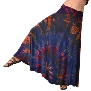 May include: A long, flowing skirt with a tie-dye pattern in shades of blue, orange, and pink. The skirt has a gathered waistband and a flowing, A-line silhouette.