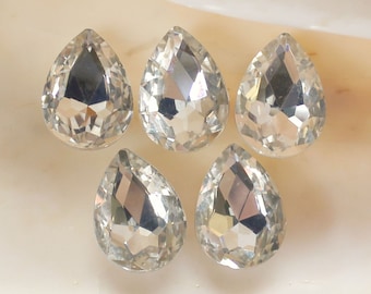 May include: Five clear teardrop-shaped crystal rhinestones. The rhinestones are faceted and have a high shine.