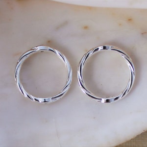 May include: Two silver rings with a twisted design. The rings are smooth and shiny.