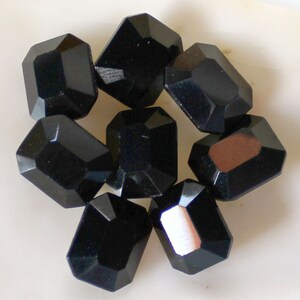 May include: Eight black faceted glass beads, each with a rectangular shape.