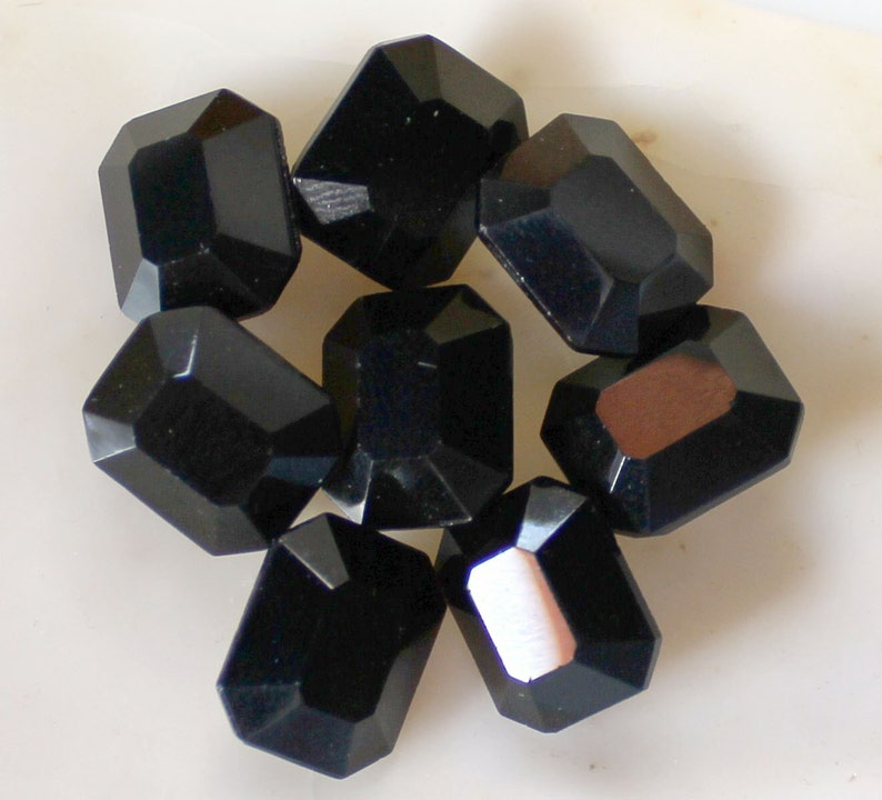 May include: Eight black faceted glass beads, each with a rectangular shape.