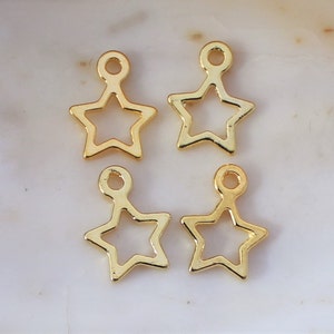 May include: Four gold-colored metal star charms with a loop at the top. The stars are hollow and have a simple design.