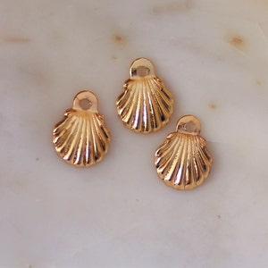 May include: Three gold-colored seashell charms with a loop at the top for attaching to jewelry or other crafts.
