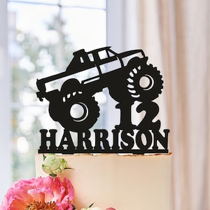 May include: Black monster truck cake topper with the number 12 and the name Harrison. The truck is on top of the number 12.
