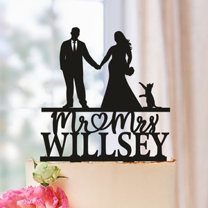 May include: Black silhouette cake topper featuring a bride and groom holding hands, a cat, and the text "Mr & Mrs Willsey".