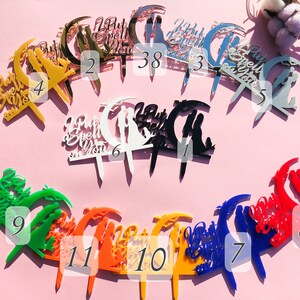 May include: Assortment of 11 acrylic cake toppers in various colors, featuring a crescent moon design with the text "I Put a Spell on You".