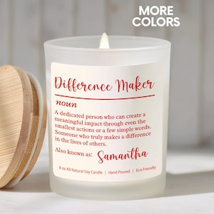 May include: A white frosted glass candle with a wooden lid. The candle has a label with the words "Difference Maker" and a definition. The name "Samantha" is also on the label. The candle is 8 oz and made of all-natural soy.