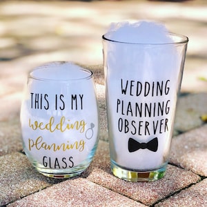 May include: Two glasses with text on them. The smaller glass is a wine glass with the text "This is my wedding planning glass". The larger glass is a pint glass with the text "Wedding planning observer" and a black bow tie.