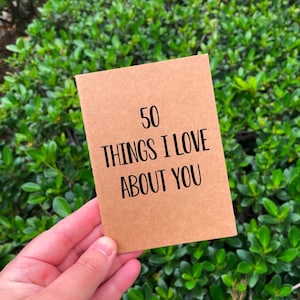 May include: A brown card with the text "50 Things I Love About You" written in black.