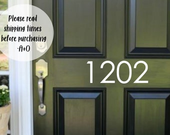 May include: A black front door with a white house number "1202" on it. The door has a silver door handle and a white sign that reads "Please read shipping times before purchasing -a+o".