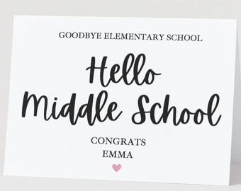 May include: A white greeting card with the text "Goodbye Elementary School" and "Hello Middle School" in black script. The card also includes "Congrats Emma" and a small pink heart.