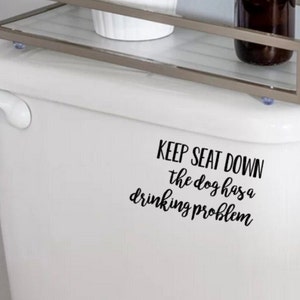 May include: White toilet tank with a black vinyl decal that reads "Keep seat down the dog has a drinking problem".