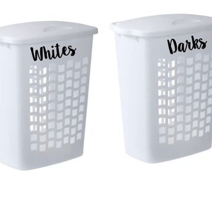 May include: Two white plastic laundry hampers with black labels. The hamper on the left is labeled "Whites" and the hamper on the right is labeled "Darks".