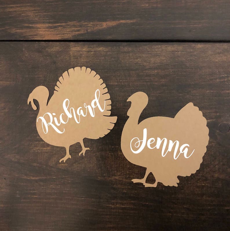 Puede incluir: Dos recortes de tarjetas de lugar de pavo de papel marr&oacute;n con los nombres Richard y Jenna escritos en blanco.